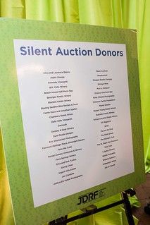 a sign that says silent auction donors in front of green curtained walls and floor