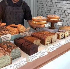 a man standing in front of a counter filled with different types of breads and pastries