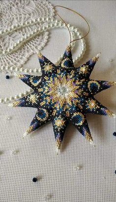 a star ornament made out of beads and pearls on a white tablecloth