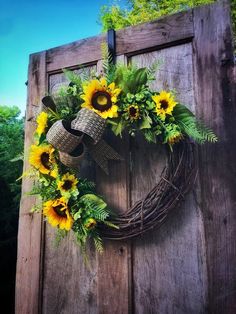 a wreath with sunflowers and bells hanging on a wooden door frame in front of trees