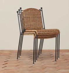 two wicker chairs sitting on top of a wooden floor next to an empty wall