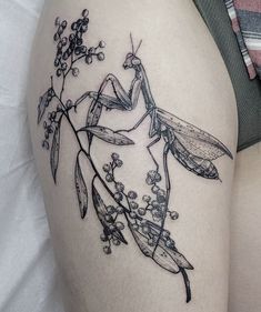 a woman's thigh with a tattoo of a praying mantisbee on it