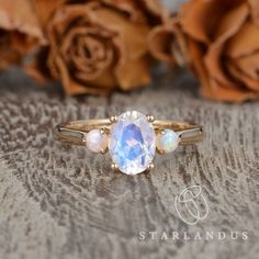 an opalite ring sits on a table next to roses