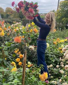 a woman is picking flowers in a garden