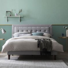 a bedroom with green walls and a bed in the middle is decorated with grey linens