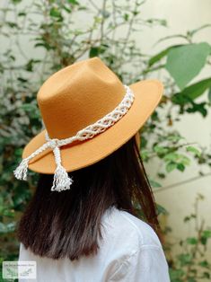 a woman wearing a orange hat with tassels on the brim and side