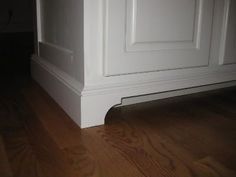 an empty room with wood flooring and white painted paneling on the door frame