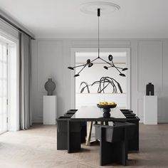 an elegant dining room with white walls and black furniture is featured in this modern home