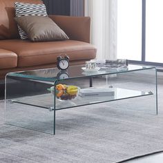 a glass coffee table sitting on top of a carpeted floor next to a couch