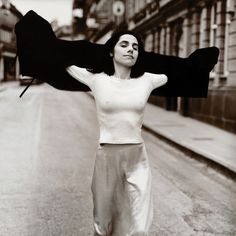 black and white photograph of woman walking down the street with her arms in the air