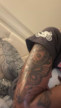 a man with tattoos on his arm laying in bed