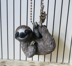 a sloth hanging from a chain on a wall