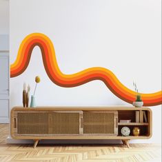 an orange and yellow wave painted on the wall next to a wooden entertainment center with bookshelves