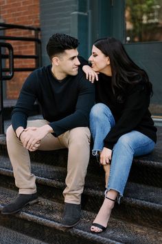 a young man and woman sitting on the steps together looking into each other's eyes