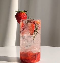 two strawberries are sitting on top of a glass with ice and water in it