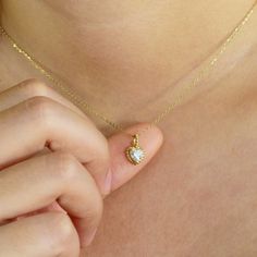 a close up of a person wearing a necklace with a heart shaped diamond on it