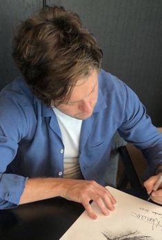 a man sitting at a table writing on paper