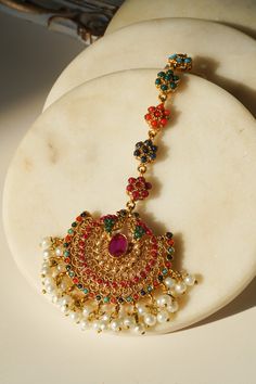 Introducing the Imaari Statement Necklace Set with Maang Tikka and Chandbali Earrings. This exquisite necklace set features multicolor navratan stones with elegant gold plating and high-quality brass filling. The set includes a stunning maang tikka and matching chandbali earrings, making it a perfect style statement for special occasions or parties. The Imaari necklace set is designed to blend tradition with elegance. The intricate design of the maang tikka and the dazzling chandbali earrings co Festive Multicolor 22k Gold Bridal Necklace, Festive Gold Temple Necklace With Multi-stone, 22k Gold Multi-stone Multicolor Jewelry, Multicolor Multi-stone 22k Gold Jewelry, Multicolor 22k Gold Kundan Temple Jewelry Necklace, Multicolor 22k Gold Kundan Necklace For Celebration, Multicolor 22k Gold Temple Jewelry Bridal Necklace, Bollywood Style 22k Gold Multicolor Jewelry, Bollywood Style Multicolor 22k Gold Jewelry