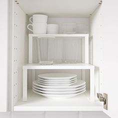 white dishes are stacked on top of each other in a kitchen cupboard with plates and cups