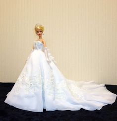 a barbie doll wearing a white dress and tiara on a black carpeted floor