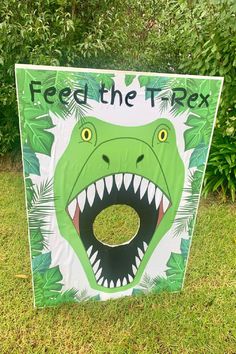 a sign that says feed the t - rex with an image of a dinosaur's mouth