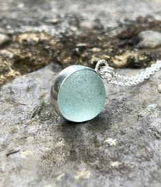 "Genuine sea glass marble in a fine silver bezel set. Hangs on a sterling silver chain 18\". Pendant width: 1.8 cm (0.7 inch) Pendant height: 2.2 cm (0.9 inch) Comes packed in a gift box. Add this adorable piece to your own jewelry collection or make a great gift for a beach lover. Some colours may vary slightly depending on your monitor configuration. If you require any further information please contact me. Thank you for visiting my shop!" Silver Glass Gemstone Jewelry, Nickel Free Silver Glass Necklace, Nickel Free Silver Necklace Of Recycled Glass, Silver Glass Jewelry With Gemstone, Silver Round Glass Jewelry, Sterling Silver Round Necklaces With Soldered Details, Round Recycled Glass Necklaces For Gifts, Silver Gemstone Necklaces For Keepsake, Silver Glass Jewelry For Keepsake