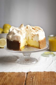 a cake on a glass plate with lemons in the back ground and a white table cloth