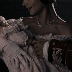 a woman holding a baby in her arms with a skull on it's shoulder