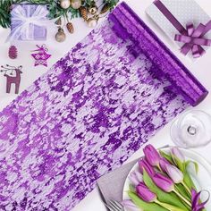 a table topped with purple flowers next to a plate of food and wrapping paper on top of it