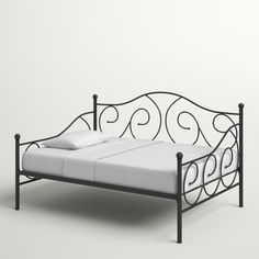 an iron bed frame with white sheets and pillows on it, against a gray background