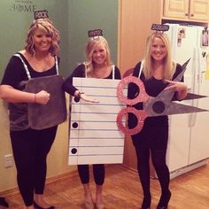 three women standing in front of a refrigerator holding giant scissors