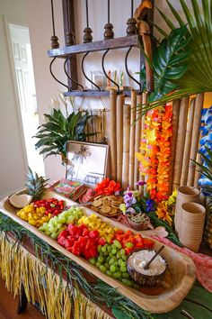 an assortment of fruits and vegetables displayed on a buffet table in a tropical themed setting