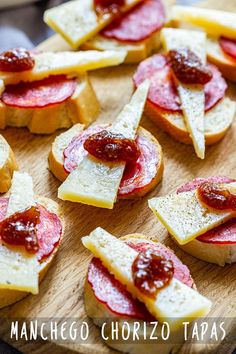 small slices of bread with cheese and jam on them sitting on a cutting board, ready to be served