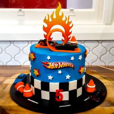 a birthday cake with hot wheels on top and flames coming out of the car's engine