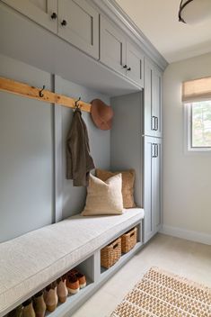 a white bench sitting under a window next to a coat rack