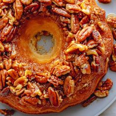 a bundt cake with pecans and nuts on it sitting on a white plate