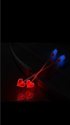 two red and blue heart shaped lights on a black surface next to a pair of scissors