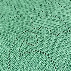 a green crocheted blanket with black dots on it