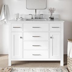 a white bathroom vanity with two sinks and mirrors on the wall, along with a rug in front of it