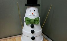 a snowman made out of plastic sitting on top of a wooden table next to a wall