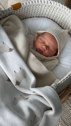 a baby is sleeping in a wicker bassinet with a white blanket on it