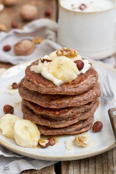 a stack of pancakes topped with bananas and nuts