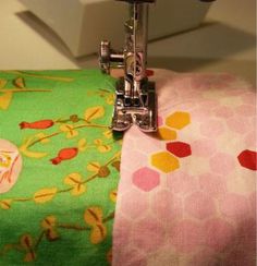 the sewing machine is on top of the colorful fabric that's being sewn