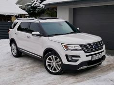 a white ford explorer parked in front of a house with snow on the ground and two garage doors