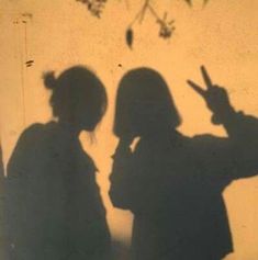 two people standing next to each other with their shadow cast on the wall behind them