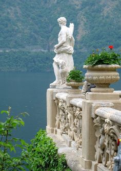 there is a statue on the side of a building next to some plants and flowers