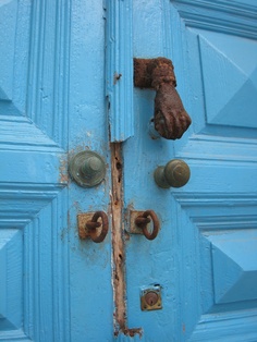 a blue door with rusted handles and knobs