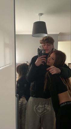 a man and woman taking a selfie in front of a mirror with their arms around each other