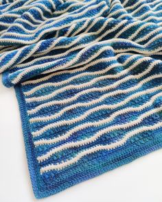 blue and white crocheted blanket laying on top of each other with wavy lines