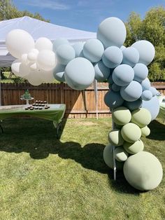 a bunch of balloons that are on the grass in front of some tables and chairs